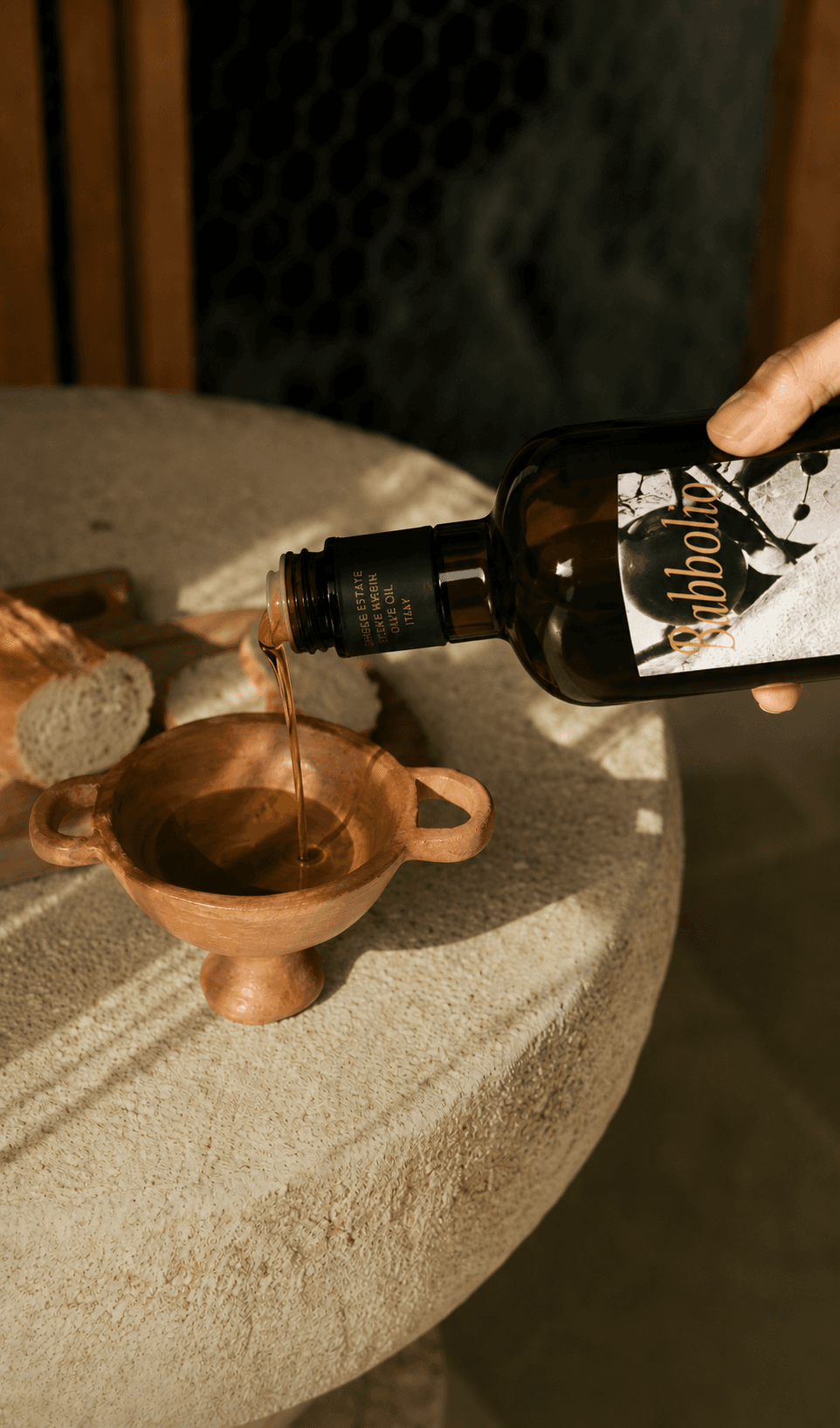 Babbolio olive oil being poured into a terracotta bowl with fresh bread
